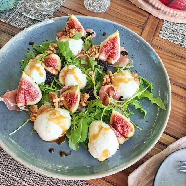Antipasti platter with figs, burrata, and arugula
