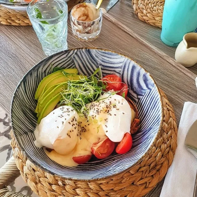 Brunch-Bowl mit pochierten Eiern und Avocado auf einem Tisch