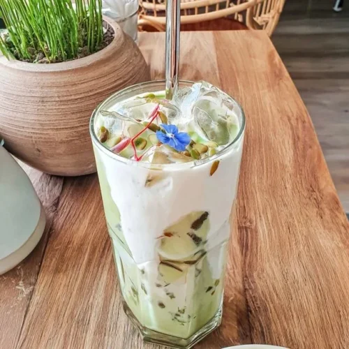 Eiskalter Matcha-Latte mit Kokosmilch in einem Glas auf einem Tisch