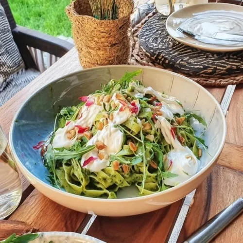 Frische Tagliatelle serviert mit Rucola-Pesto auf einem weißen Teller