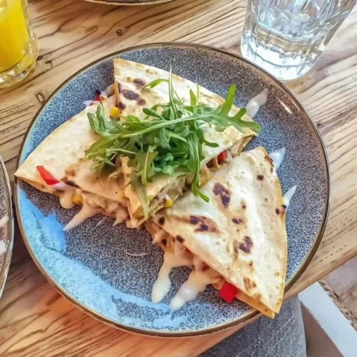 Käse-Quesadilla mit Mais und Paprika auf einem Teller serviert