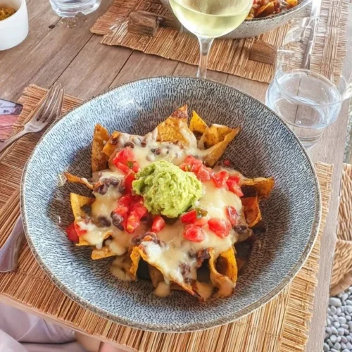 Leckere Nachos mit Guacamole und frischer Salsa auf einem Teller.