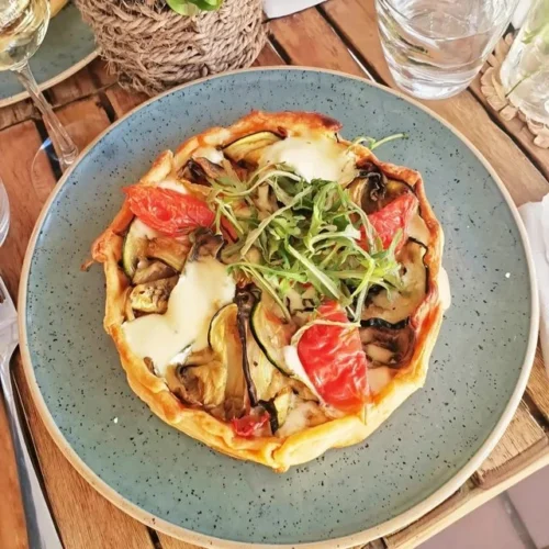 Tarte mit gegrilltem Gemüse und Ziegenkäse auf einem Teller serviert