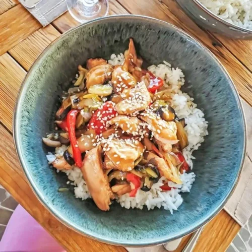 Teriyaki-Chicken mit Gemüse und Reis auf einem Teller serviert.
